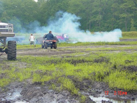1995 Dodge 1500 - Several vehicles are engaged in off-road activities, creating a large cloud of smoke in a grassy, muddy area.