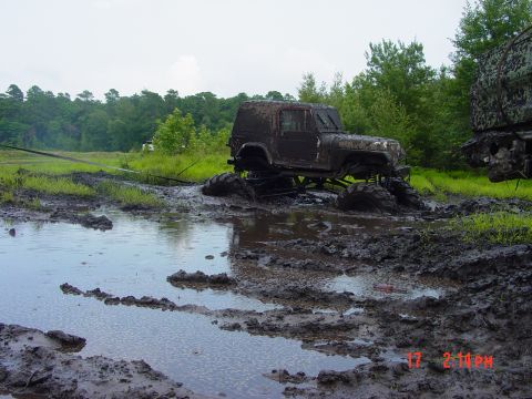 1995 Dodge 1500 - An off-road vehicle is deeply stuck in a muddy mire, with another vehicle partially visible on the right.