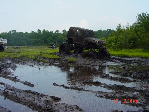 1995 Dodge 1500 - An off-road vehicle is deeply stuck in thick mud and water, with another vehicle visible in the background.