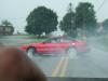 1997 Ford Probe - Red car skidding on a wet road with trees and houses in the background.