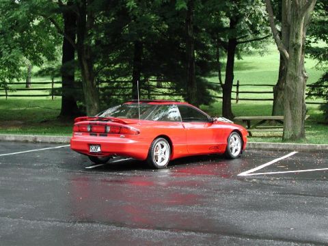 1997 Ford Probe - A red 1997 Ford Probe GTS is parked in a lot after a rain shower.
