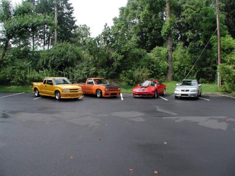 1997 Ford Probe - Four vehicles are parked in a lot with trees in the background.