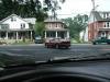 1997 Ford Probe - A red van is visible driving down a street with houses on either side. Another vehicle is parked on the right.