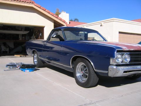 1969 Ford Ranchero - A blue 1969 Ford Ranchero with a partially primed hood sits in a driveway in front of a garage.