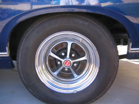 1969 Ford Ranchero - Close-up of a chrome five-spoke wheel with a red center cap on a blue vehicle.