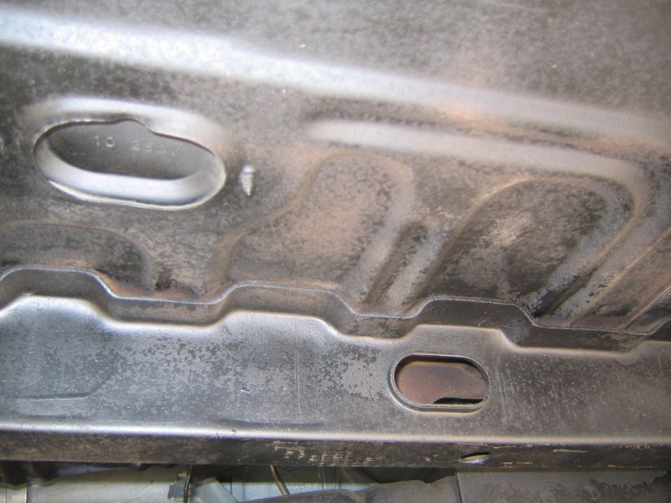 Underside of a vehicle with some stamped metal and an oval opening. Text '10 24-1' is visible