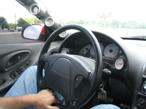1994 Ford Probe - Interior view of a car, focusing on the steering wheel and dashboard gauges, with a glimpse of the exterior through the side window.