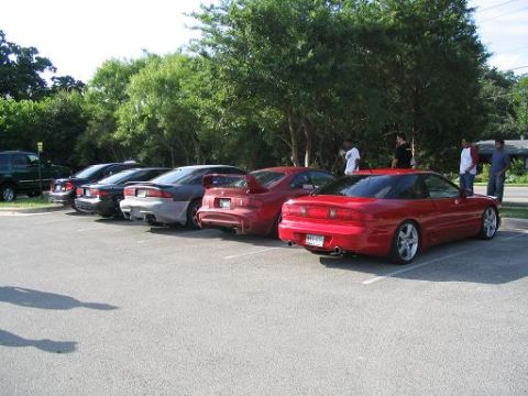 1994 Ford Probe - A line of cars is parked in a lot, with a red 1994 Ford Probe prominently featured in the foreground.