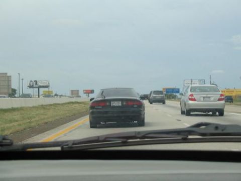 1994 Ford Probe - A black sedan is seen from behind while driving on a highway with other vehicles.