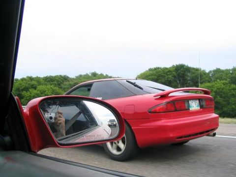 1994 Ford Probe - A red coupe is seen driving on the highway, with another car visible in the distance.