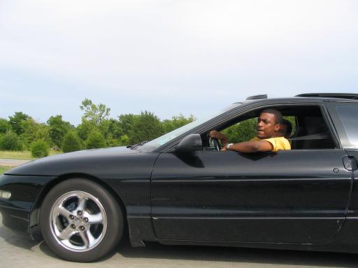 Man driving a black 1994 Ford Probe from the side