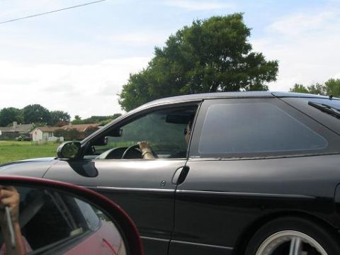 1994 Ford Probe - Side view of a black 1994 Ford Probe with a driver behind the wheel, seen from another vehicle.