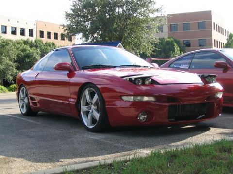 1994 Ford Probe - A red 1994 Ford Probe is parked in a lot, showing its front 3/4 view with pop-up headlights visible.