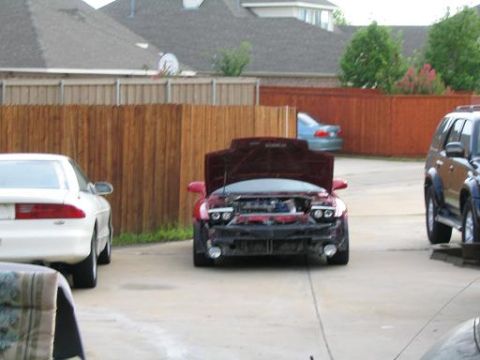 1994 Ford Probe - A red car with its hood open is parked in a driveway next to other vehicles.