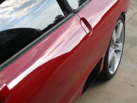 1994 Ford Probe - Side view of a red car's door and wheel, with sky reflected in the window.