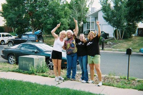 1972 Ford Ranchero - Four women celebrate on a suburban street with a dark green car parked nearby.