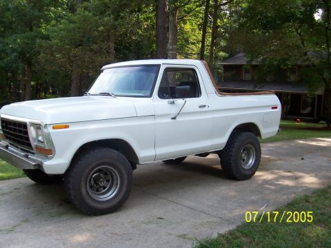1979 Ford Bronco - White 1978 Ford Bronco parked on a driveway with trees and a house in the background.