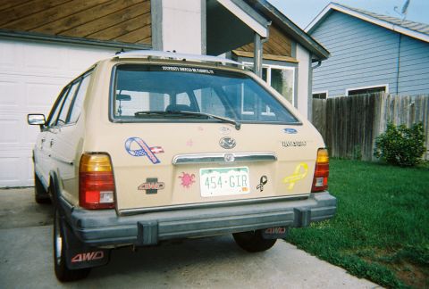 1972 Ford Ranchero - Rear view of a tan station wagon with multiple stickers and a license plate reading '454-GIR'.