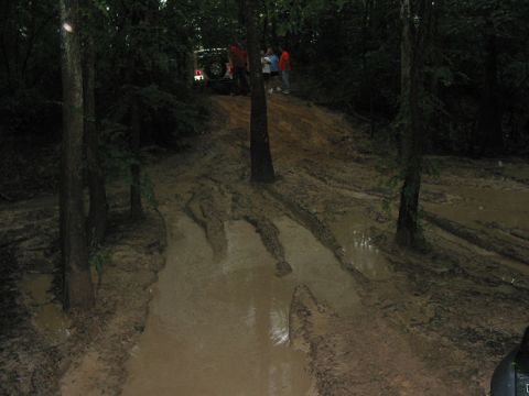 2000 Jeep Grand Cherokee - Off-road vehicle navigating a very muddy and rutted trail in a wooded area.