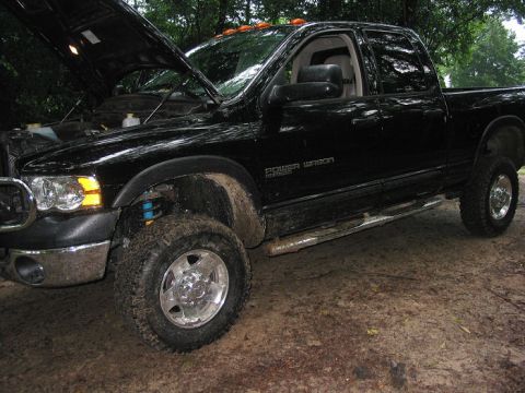 2000 Jeep Grand Cherokee - Black Dodge Ram 2500 Power Wagon pickup truck with hood open, parked outdoors.
