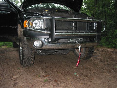 2000 Jeep Grand Cherokee - This black pickup truck is parked on a muddy, wooded area with its hood up and a bull bar attached to the front.
