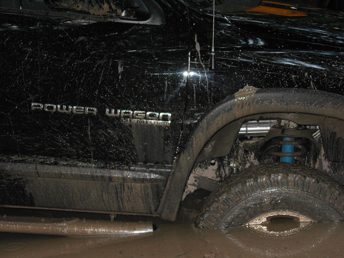Mud-splattered black truck side with 'Power Wagon' and 'HEMI 5.7L' badges visible