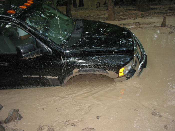 Black pickup truck with 'Power Wagon' badging stuck in deep mud
