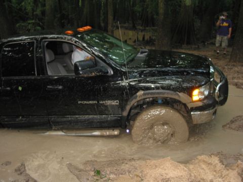 2000 Jeep Grand Cherokee - A black pickup truck is stuck in deep mud, with its front wheel almost completely covered.