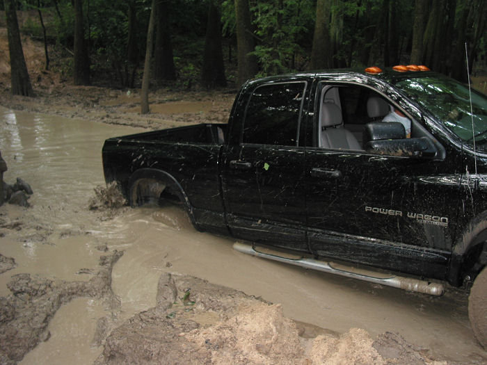 Black pickup truck with "Power Wagon" badging driving through deep mud