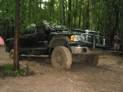 2000 Jeep Grand Cherokee - Black Dodge Ram pickup truck stuck in mud during an off-road event.