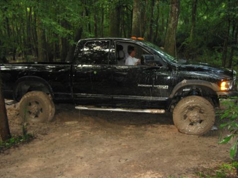 2000 Jeep Grand Cherokee - A black pickup truck is stuck in the mud while driving through a wooded area.