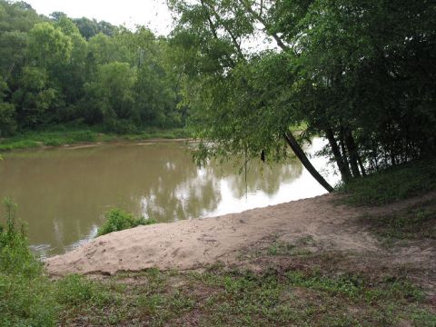 2000 Jeep Grand Cherokee - A peaceful scene of a river flowing through a wooded area with a sandy embankment.
