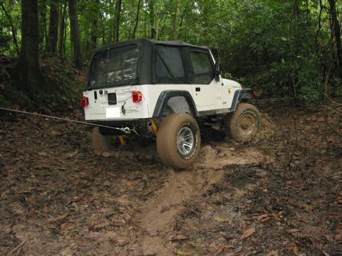 2000 Jeep Grand Cherokee - This Jeep Wrangler is navigating a challenging muddy terrain, with its tires deep in the muck.