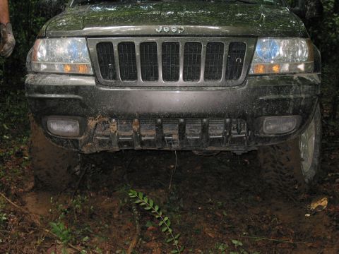 2000 Jeep Grand Cherokee - Front view of a muddy 2000 Jeep Grand Cherokee navigating off-road terrain.