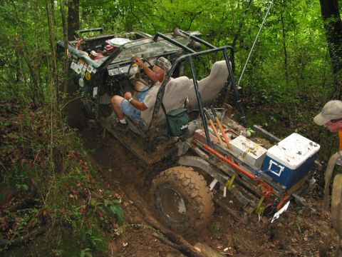 2000 Jeep Grand Cherokee - An off-road vehicle navigates a difficult muddy path through a dense forest.