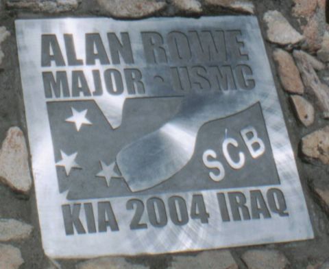 1966 Ford Bronco - A brushed-metal memorial plaque laid into a stone surface, etched "ALAN ROWE MAJOR - USMC" above an SCB club logo with stars and a stylized…