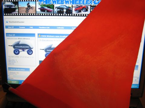 1990 Ford Bronco - red decal is held in front of a laptop displaying TheWebWheeler.com forum with a vehicle photo banner.