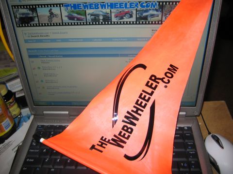 1990 Ford Bronco - orange die-cut sticker reading TheWebWheeler.com rests on a laptop keyboard in front of the forum site.