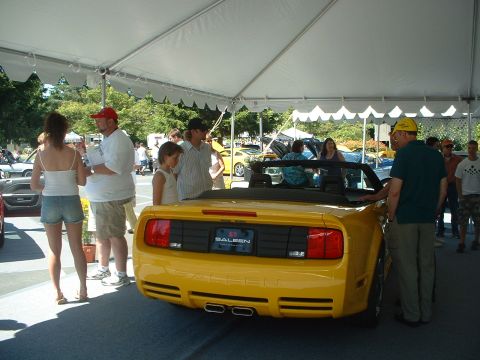 1999 Ford Crown Victoria - A yellow Saleen convertible is displayed under a tent at a car show with spectators around.