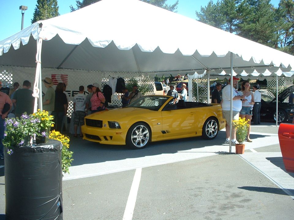 Yellow convertible Mustang parked under a tent at a car show