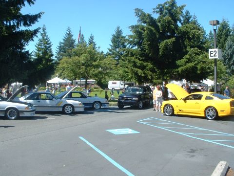 1999 Ford Crown Victoria - A yellow Ford Mustang GT is displayed at an outdoor car show with other vehicles.