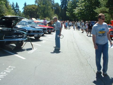 1999 Ford Crown Victoria - Cars are parked in a lot at a Ford show, with people milling around.
