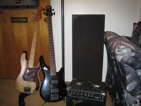 1990 Ford Bronco - natural-finish and a black electric bass guitar lean beside a tall speaker and a small Fender practice amp.