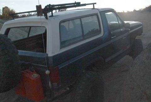 1986 Ford Bronco - Ford Bronco navigating rough terrain with auxiliary fuel can and roof rack.