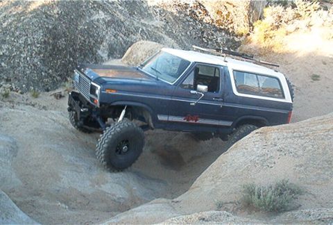 1986 Ford Bronco - This modified SUV navigates a rocky terrain with its large tires and lifted suspension.