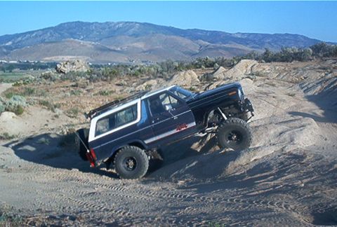1986 Ford Bronco - This 1986 Ford Bronco navigates a challenging rocky trail under a clear blue sky.