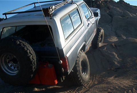 1986 Ford Bronco - Ford Bronco navigates a rocky trail with a spare tire and auxiliary fuel can mounted.