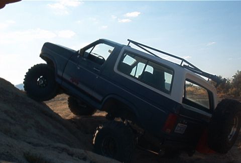 1986 Ford Bronco - This SUV is shown navigating a steep, rocky terrain under a clear sky.