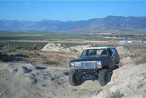 1986 Ford Bronco - This 1980s Ford Bronco navigates a , off-road landscape under a clear blue sky.