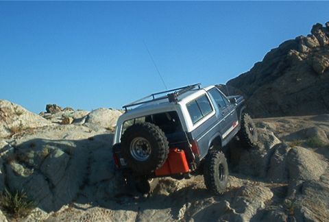1986 Ford Bronco - This 1986 Ford Bronco navigates a rocky trail, its off-road capabilities with a rear-mounted spare tire and auxiliary fuel can.